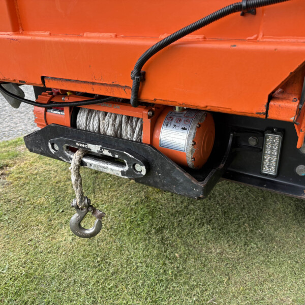 Close-up of an orange industrial trailer with a rope winch and a metal hook hanging from its lower edge