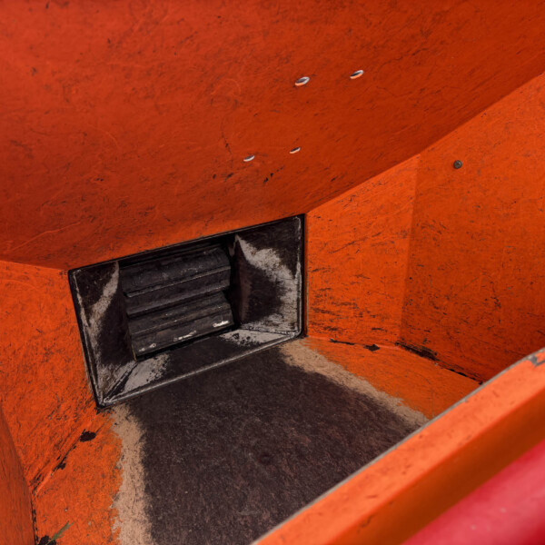Close-up of an orange, worn metal staircase with a dark metal step and visible grime and scratches.