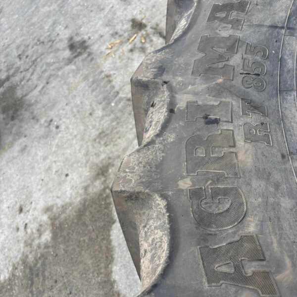 Close-up of a dusty tire with large embossed letters along the sidewall resting on rough pavement.