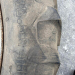 Close-up of a dusty tire sidewall with embossed numbers and symbols visible on the worn rubber point of view outside.