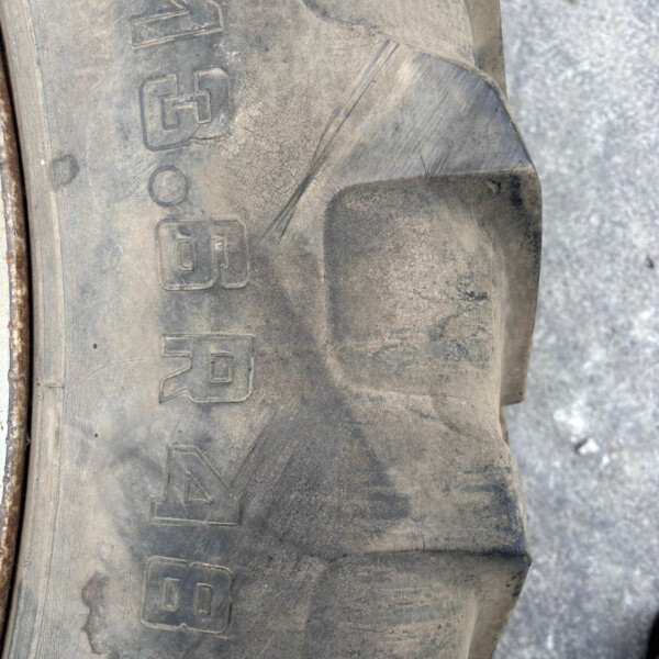 Close-up of a dusty tire sidewall with embossed numbers and symbols visible on the worn rubber point of view outside.