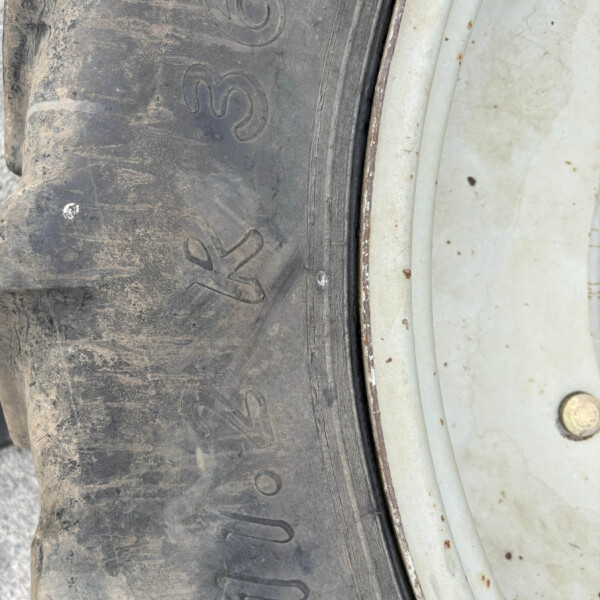 Close-up of a dusty black tire with embossed numbers beside a rusted metal rim edge.