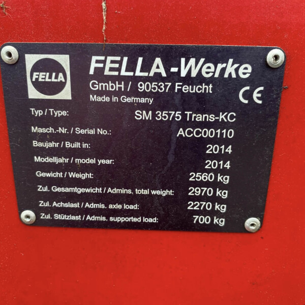 Metal identification plate on a red surface showing model, serial, year, and weight specs (German/English). Accuracy: FELLA-Werke label with types and weights visible.