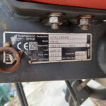 Close-up of a rusty nameplate on a Kverneland Group spreader, showing the model and serial plate.