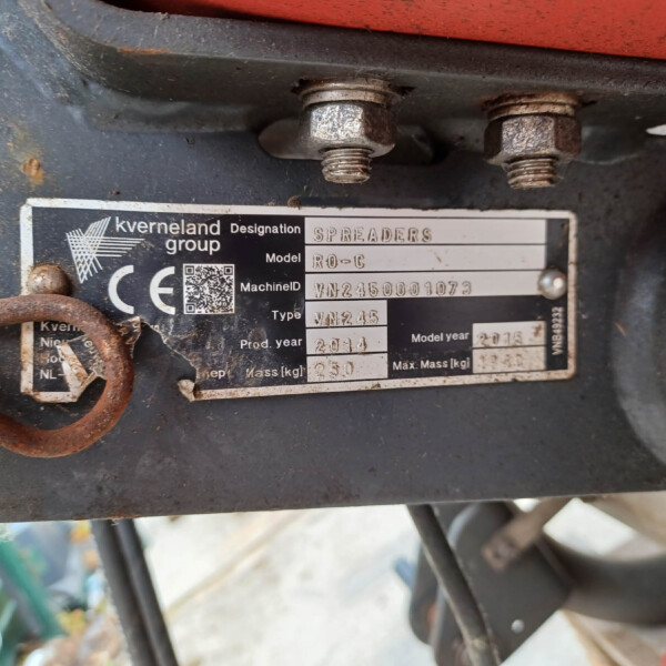 Close-up of a rusty nameplate on a Kverneland Group spreader, showing the model and serial plate.