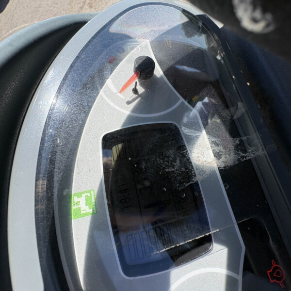 Close-up of a gray helmet visor with a red strap tab, viewed from above on a surface.