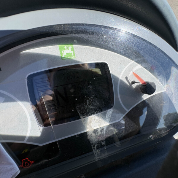 Close-up of a silver-gray helmet visor with a small green safety sticker and a red gauge visible through the glass.