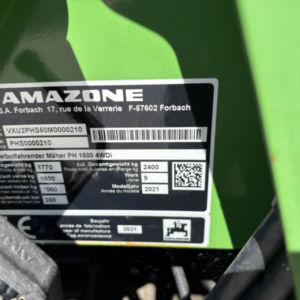 Close-up of a black identification plate on green agricultural equipment displaying the brand AMAZONE, model PH 1500 4WDi, serial numbers and a barcode/QR area.