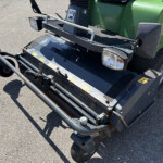 Front view of a green utility vehicle with bumper bar, headlights, and metal guard on a paved surface