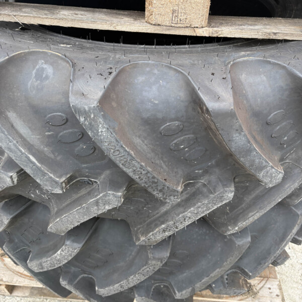 Stack of large black industrial tires stacked on wooden pallets, showing deep tread patterns and sidewalls