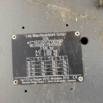 Metal machinery nameplate with model and weight data, dirty from use on a gray surface.