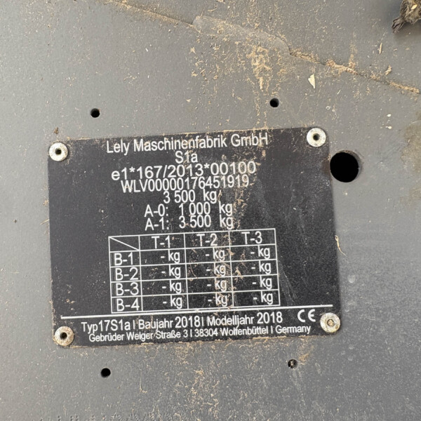 Metal machinery nameplate with model and weight data, dirty from use on a gray surface.