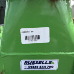 Close-up of a bright green machine with a white barcode label and a Russells sticker visible on the surface.