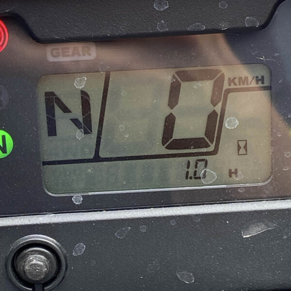 Close-up of a vehicle instrument panel showing the gear indicator in Neutral (N), with a digital KM/H readout on the right and a green neutral light visible. The surface is dusty with small smudges.