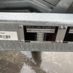 Close-up of a metal trailer identification plate on an Ifor Williams trailer, showing the brand name, weight data, and a nearby barcode sticker.