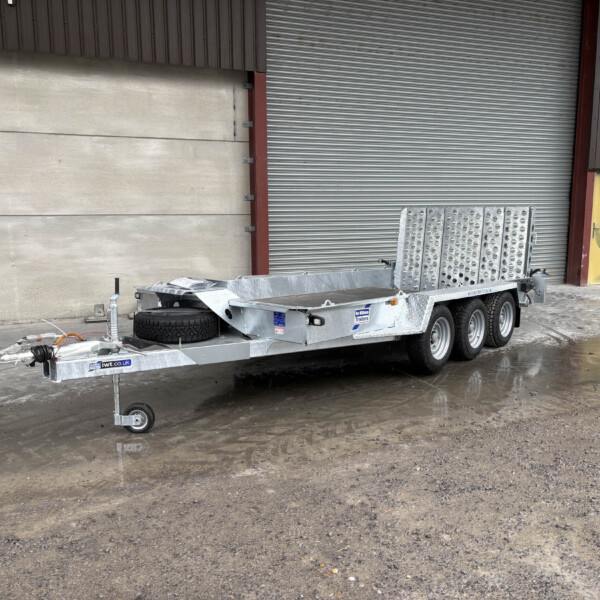 Metal loading trailer parked in a wet industrial yard with a large corrugated metal door and yellow access door in the background.