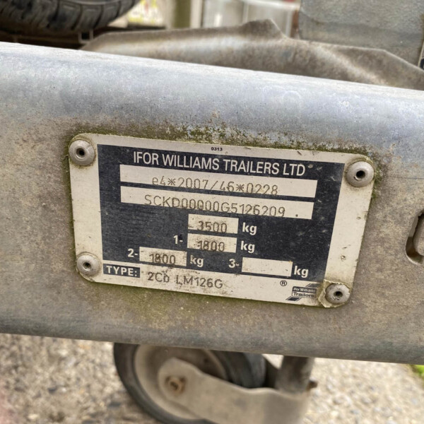 Close-up of a dusty metal plate on a trailer frame showing the brand 'Ifor Williams Trailers Ltd' and weight specifications.