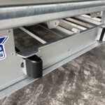 Close-up of a galvanized trailer frame with a metal roller and a rectangular side light; Williams Trailers logo is visible.