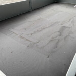 Metal platform with diamond-plate flooring and grey walls; a small white bag rests in the upper-right corner.