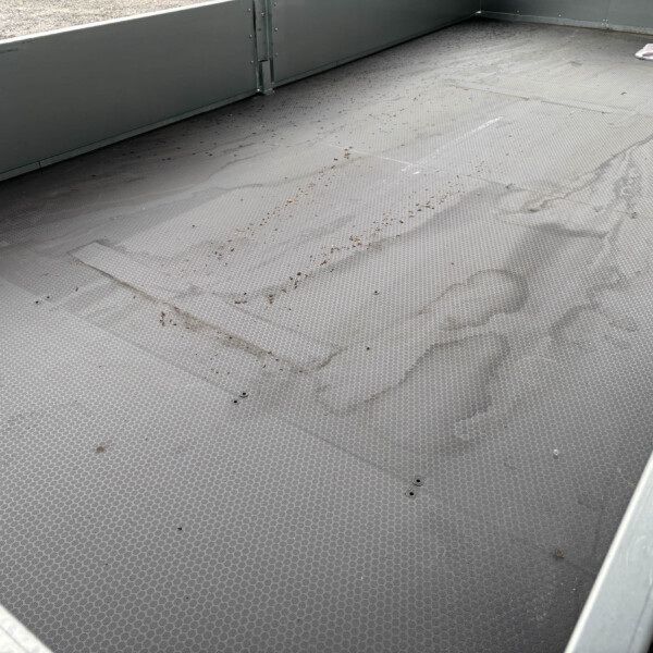 Metal platform with diamond-plate flooring and grey walls; a small white bag rests in the upper-right corner.