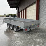 Silver metal trailer parked outside a warehouse with a wide corrugated shutter door