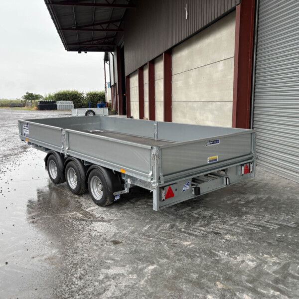Silver metal trailer parked outside a warehouse with a wide corrugated shutter door