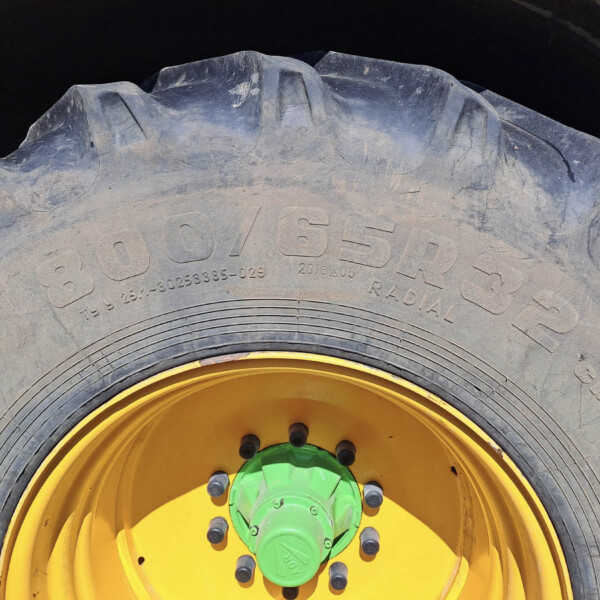 Close-up of a large tractor tire with a bright yellow rim and green center, dusty and worn surface visible.