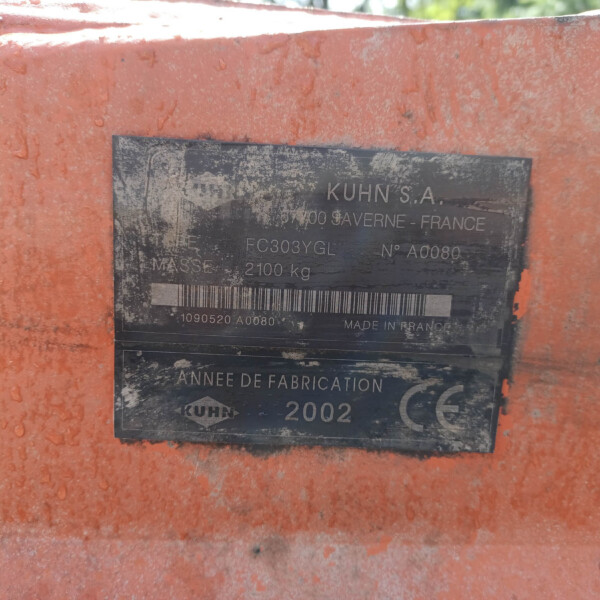 Close-up of a dirty black identification plate on an orange machine, showing KUHN S.A. and 'Made in France' text.