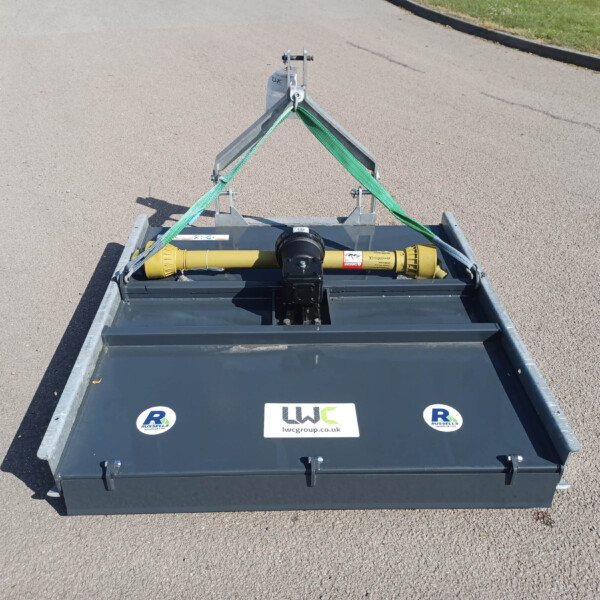 Top-down view of a gray trailer carrying industrial equipment, with a yellow hydraulic unit and green securing straps on a paved surface