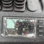 Close-up of a car's instrument cluster under a rain-speckled dashboard, showing temperature and fuel gauges.