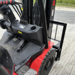 Forklift operator's cabin with control levers, ignition key, and foot pedals visible in an outdoor lot.