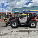 Tractor dealership lot with multiple tractors parked outside a blue New Holland Agriculture building.
