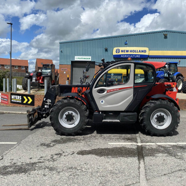 Tractor dealership lot with multiple tractors parked outside a blue New Holland Agriculture building.