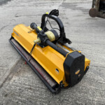 Yellow plate compactor on a concrete surface, showing its handle, engine, and protective guard for pavement work (outdoor industrial setting).