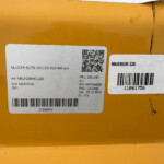 Close-up of an orange box with white labels showing a QR code, a barcode, and the text 'MAGNUM 225' and other product details.