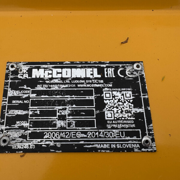 Weathered black identification plate on a yellow surface, showing model, serial number, QR code, and 'Made in Slovenia' label.