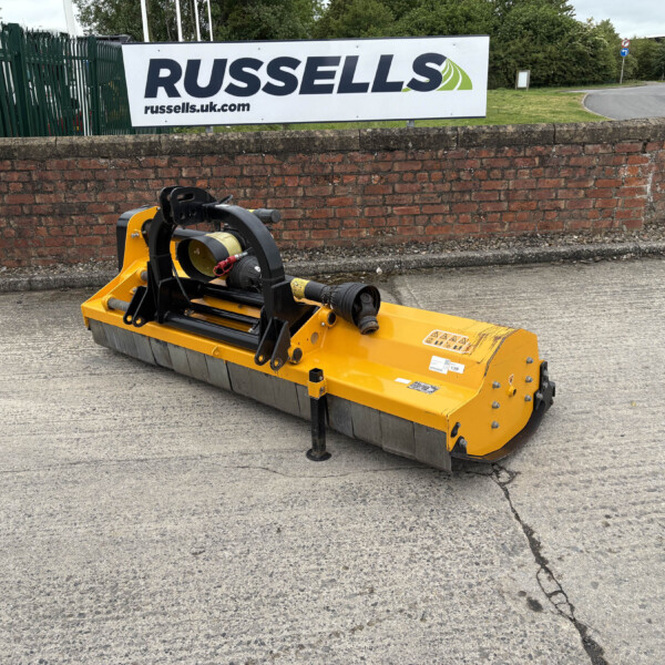 Yellow industrial attachment parked on a concrete surface with a red brick wall and a Russell's banner in the background.