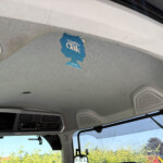 Blue tree-shaped car air freshener hanging from the rearview mirror inside a vehicle.