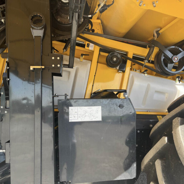 Industrial machine interior: yellow metal framework with belts, pulleys, levers, and a large tire visible on the right side