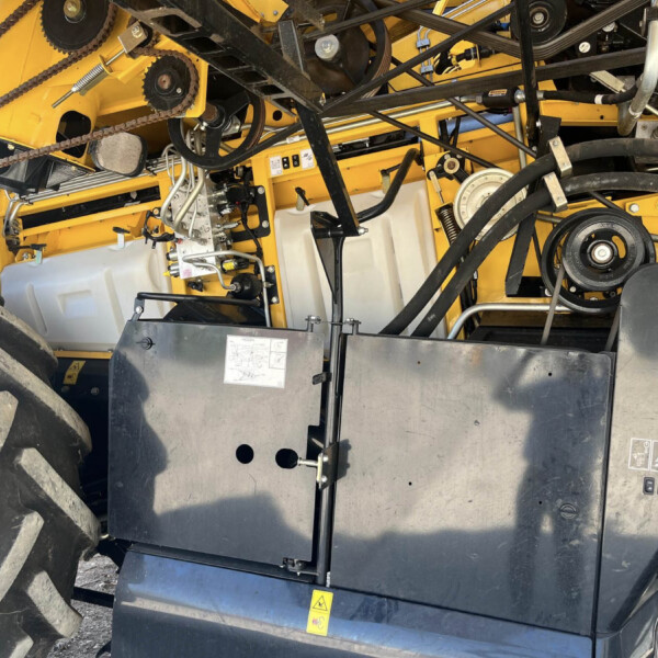 Inside view of a yellow agricultural machine showing belts, pulleys and hydraulic lines nestled in the frame.