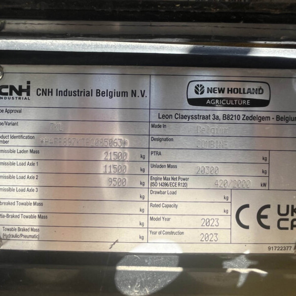 Close-up of a silver identification plate on agricultural machinery showing CNH Industrial Belgium and New Holland Agriculture logos with model and specification fields from the data plate.