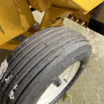 Close-up of a large tire on yellow construction equipment, with bits of ice on the tread surface.