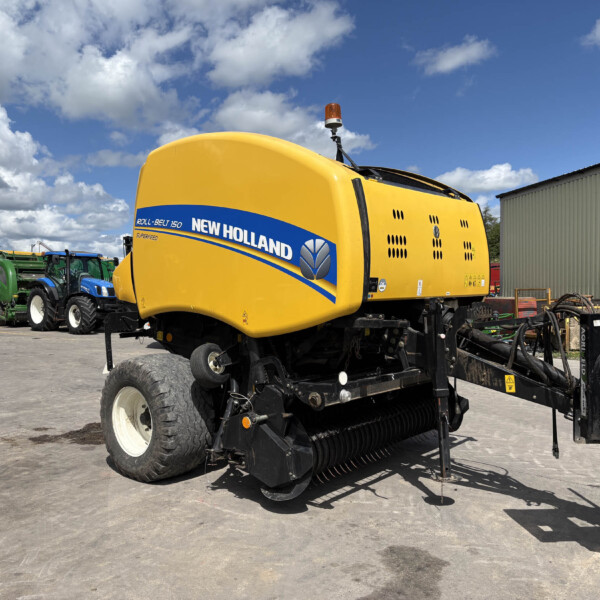 Yellow New Holland combine harvester with blue logo parked among tractors in an outdoor lot under a blue sky with clouds.