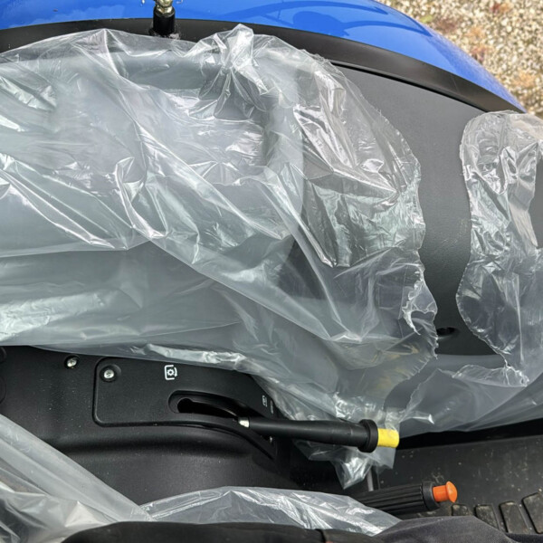 Blue car interior covered in clear plastic wrap, protecting seats and controls during maintenance or transport.