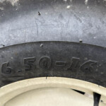 Close-up of a dirty tire showing the embossed size 650-16 and part of the wheel rim.