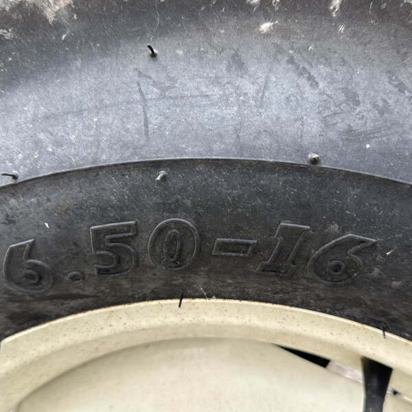 Close-up of a dirty tire showing the embossed size 650-16 and part of the wheel rim.
