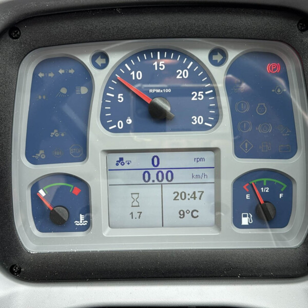 Dashboard of a vehicle showing a central RPM gauge, digital display, and warning icons on blue panels.