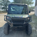 Front view of a green Polaris Ranger UTV with large tires and a protective bumper, parked on gravel outdoors.