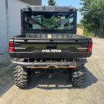 Rear view of a Polaris diesel pickup with a large empty cargo bed and oversized off-road tires.
