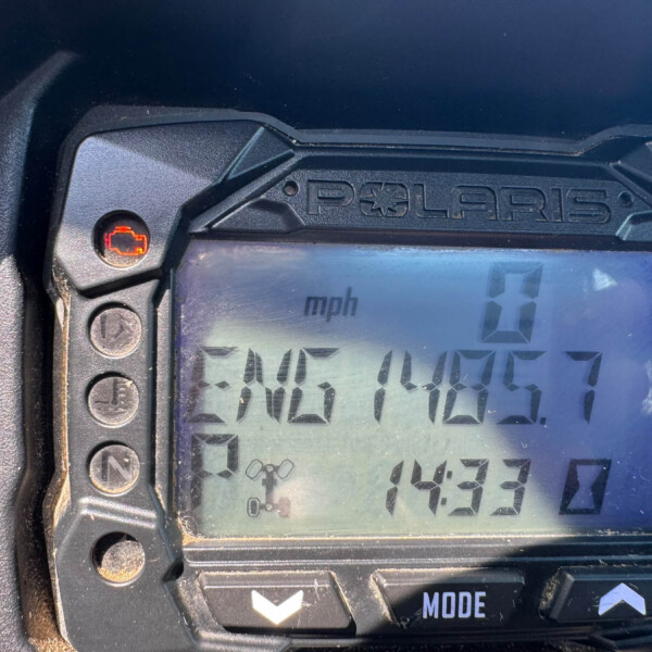 Close-up of a Polaris gauge cluster with an illuminated red warning light near the edge of the display.